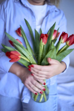                    medium-sized woman holds a bouquet of red tulips in her hands           