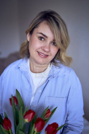 medium-sized woman holds a bouquet of red tulips in her hands