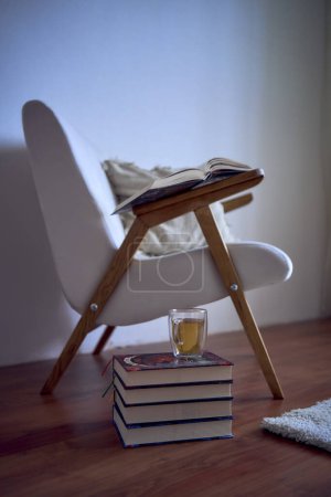                 perfect  place for reading and relaxing, a white armchair surrounded by books in a bright room        