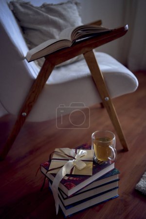                               ein Geschenkgutschein neben einem perfekten Ort zum Lesen und Entspannen, ein weißer Sessel umgeben von Büchern in einem hellen Raum         