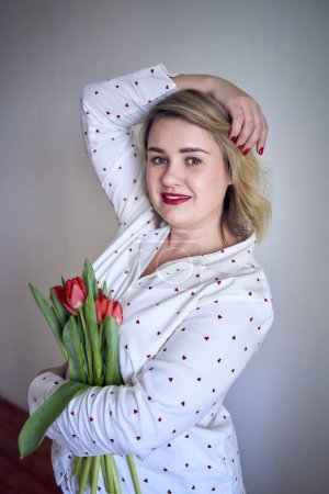          a portrait of a beautiful medium-sized woman in pajamas with a bouquet of red tulips in a minimalist style                      