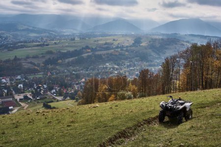 Photo for Gray quad bike on the mountain slope overlooking city below - Royalty Free Image