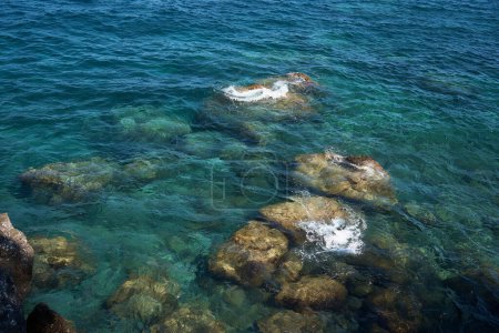               die Steine, die vom sauberen, transparenten, blauen Wasser des Mittelmeeres gewaschen werden