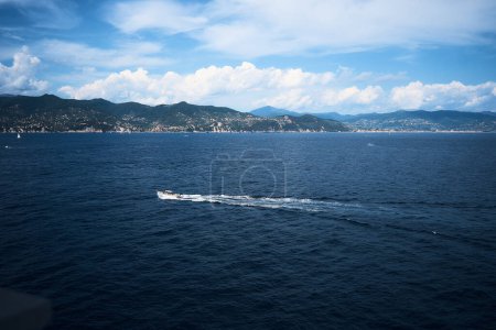               yacht leaves behind a white trail in the blue waters of the Mediterranean Sea                 