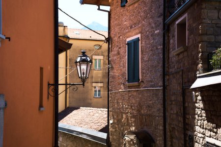         Laterne zwischen Häusern mit geschlossenen Rollläden in italienischer Sommerstadt, Detail, Hintergrund  
