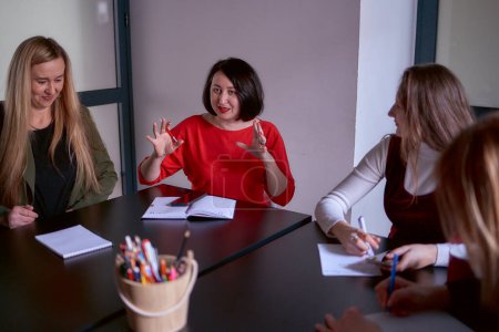 Frau im roten Pullover gestikuliert emotional bei Besprechung im Büro                         