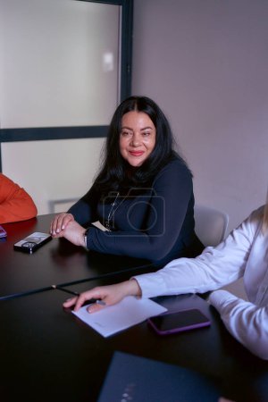 eine Plus-Size-Frau im schwarzen Kleid bei einem Meeting im Büro                  