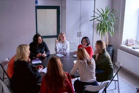  equipo de 8 mujeres incluyendo una persona con una discapacidad en una reunión en la oficina, vista superior             