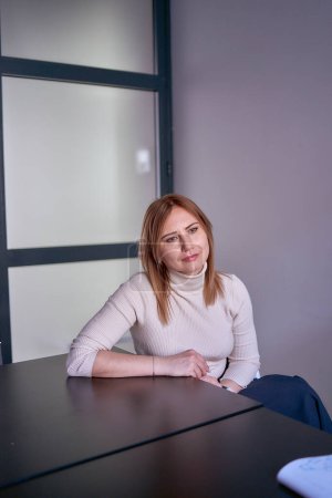               mujer rubia en un suéter ligero en una reunión en la oficina                 