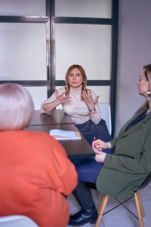 Foto de Mujeres, incluida una persona con discapacidad, discuten la estrategia de la empresa en una reunión en la oficina - Imagen libre de derechos