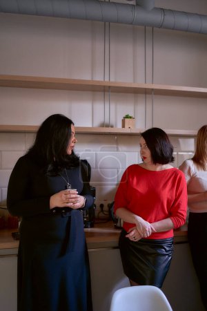                     two women talking over coffee in the office kitchen           