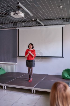 woman giving emotional speech on stage, performance hall in office                   