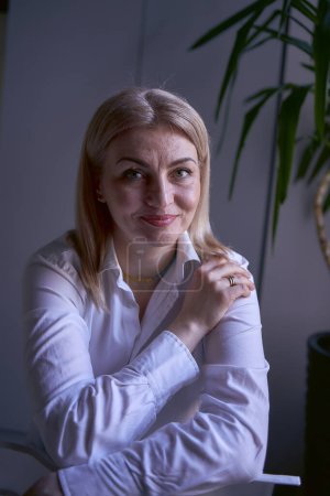             portrait d'une femme blonde en jeans et chemise blanche au bureau                   