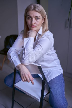 Téléchargez les photos : Portrait d'une femme blonde en jeans et chemise blanche au bureau - en image libre de droit