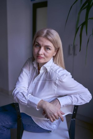             portrait of a blonde woman in jeans and a white shirt in the office                   