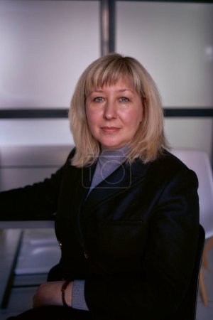  Porträt einer blonden Frau mittleren Alters im Businessanzug im Büro               