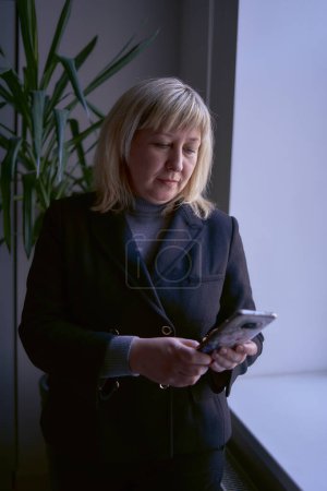 portrait of a blonde middle age woman in a business suit in the office               