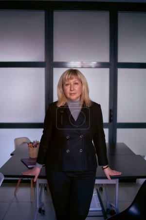  portrait of a blonde middle age woman in a business suit in the office               
