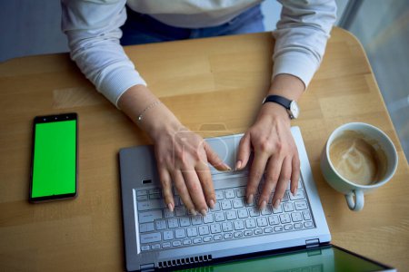 Téléchargez les photos : Un ordinateur portable et un téléphone avec écran vert sur une table de travail unique, clé chromatique, - en image libre de droit