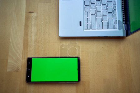       Laptop und Telefon mit grünem Bildschirm auf einem einzigen Arbeitstisch, Chroma-Schlüssel,                         
