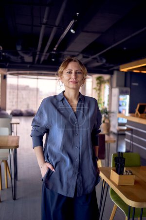  attractive middle age woman walks in a modern coworking neutral design, wearing wide leg pants and a silk blouse                           