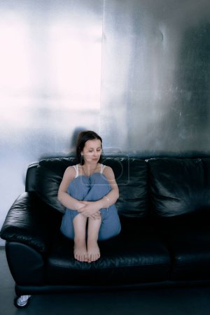 una joven adolescente luchando contra el cáncer de cerebro en sesión de fotos en el estudio, pared de metal, reflexión, sofá negro