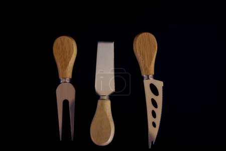set of fish and cheese knives with a wooden handle on a black background