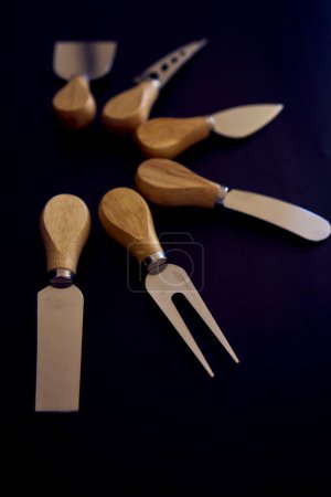 Téléchargez les photos : Ensemble de couteaux à poisson et fromage avec une poignée en bois sur fond noir - en image libre de droit