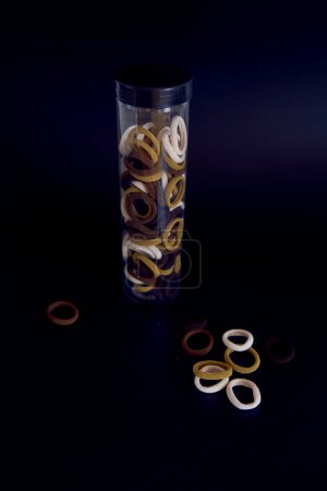 a plastic tube with hair bands on a black background