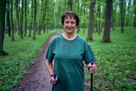 una anciana se dedica a caminar nórdico con palos en el bosque de primavera