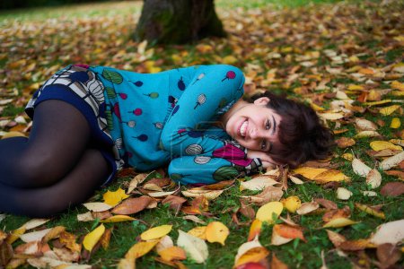 Téléchargez les photos : Fille dans une robe avec des ballons se trouve sur le sol recouvert de feuilles d'automne - en image libre de droit