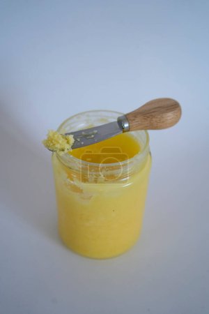        butter ghee in a transparent jar with homemade bread on white background                        