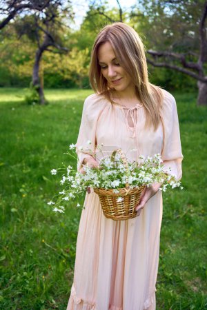 Photo for Portrait of a beautiful woman in a peach fuzz dress with a basket of flowers - Royalty Free Image