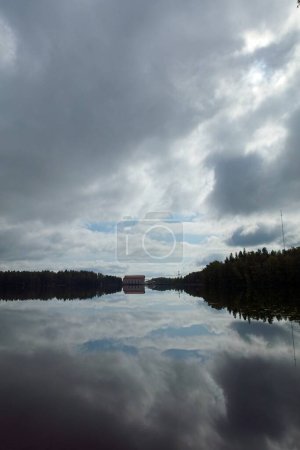 Foto de Vista del río Kymijoki con la central hidroeléctrica Ahvenkoski en el fondo con reflejo del cielo en la superficie del agua, Pyht, Finlandia. - Imagen libre de derechos