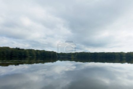 Photo for ICM abstract of landscape view of lake, forest and sky with cloudy sky reflection water surface. - Royalty Free Image