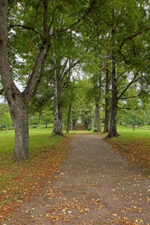 Chemin de gravier avec arbres plantés au parc du manoir Hakunila par temps nuageux d'automne, Vantaa, Finlande.