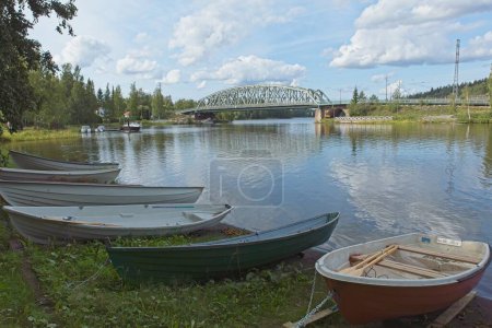 Photo for View of lake Vanajavesi with rowing boats on shore and railway bridge in the background in summer, Hmeenlinna, Finland. - Royalty Free Image