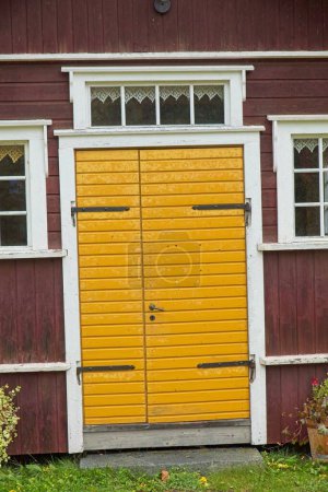 Old yellow wood door on traditional red painted building.
