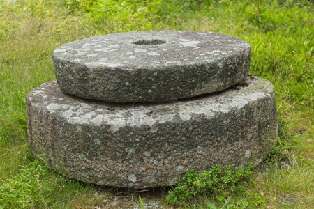 Closeup of two old mill stones on the ground.
