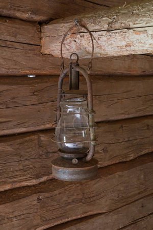 Closeup of an old fashioned storm lantern hanging in a wooden barn.