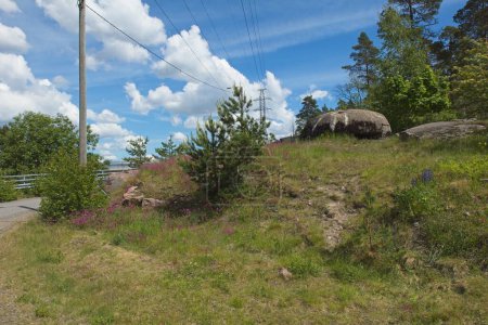 WW1 bunker on a small hill with trees, grass and clouds in sky, Ruukinranta, Espoo, Finland.