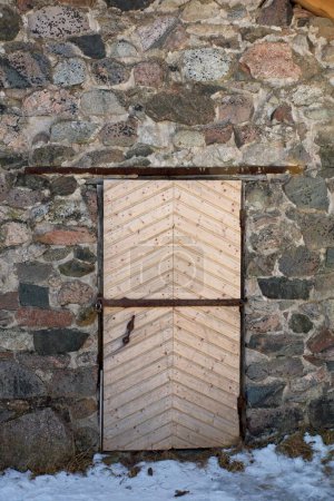 Porte en bois barrée sur un vieux bâtiment en pierre.