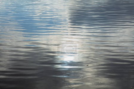 Reflections of clouds in the sky on water surface with small ripple.