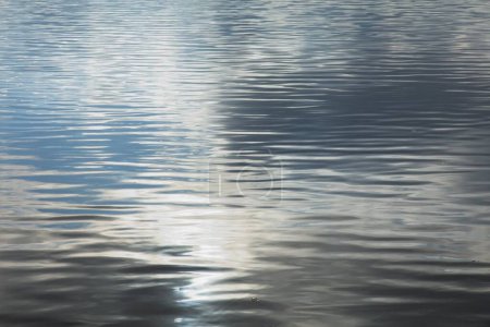 Reflections of clouds in the sky on water surface with small ripple.