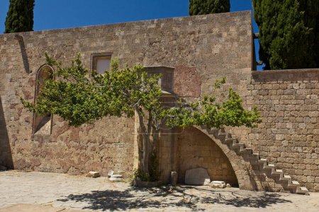 View of stone stairs and tree in sunny spring weather at medieval Filerimos Monastery, Rhodes, Greece.