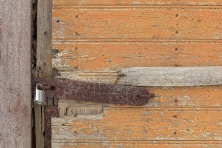 Nouveau cadenas avec loquet rouillé sur une vieille porte en bois.