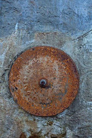 A rusty metal plate on a stone wall.