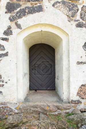 Details einer alten Holztür in einer Steinmauer.
