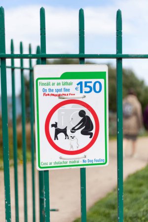 No dog fouling road sign with green frame and penalty price on a green fence