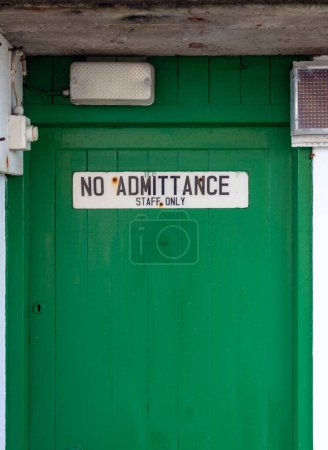 No admittance staff only sign with lamps and electrical wires on a green door.